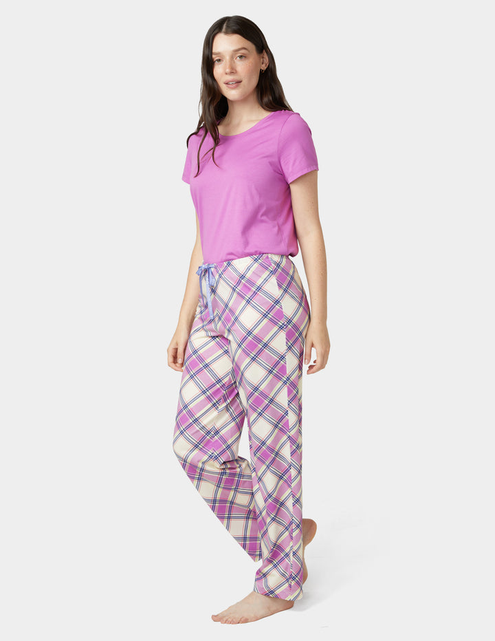 Woman wearing a pink top and plaid pants on a white background