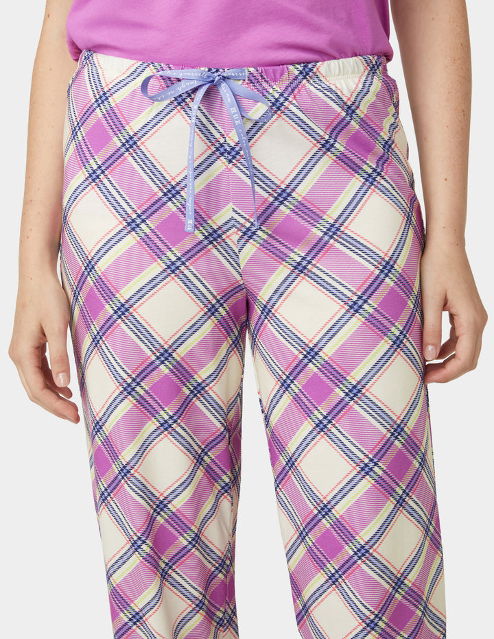 Person wearing pink and white plaid pants with a purple top on a white background