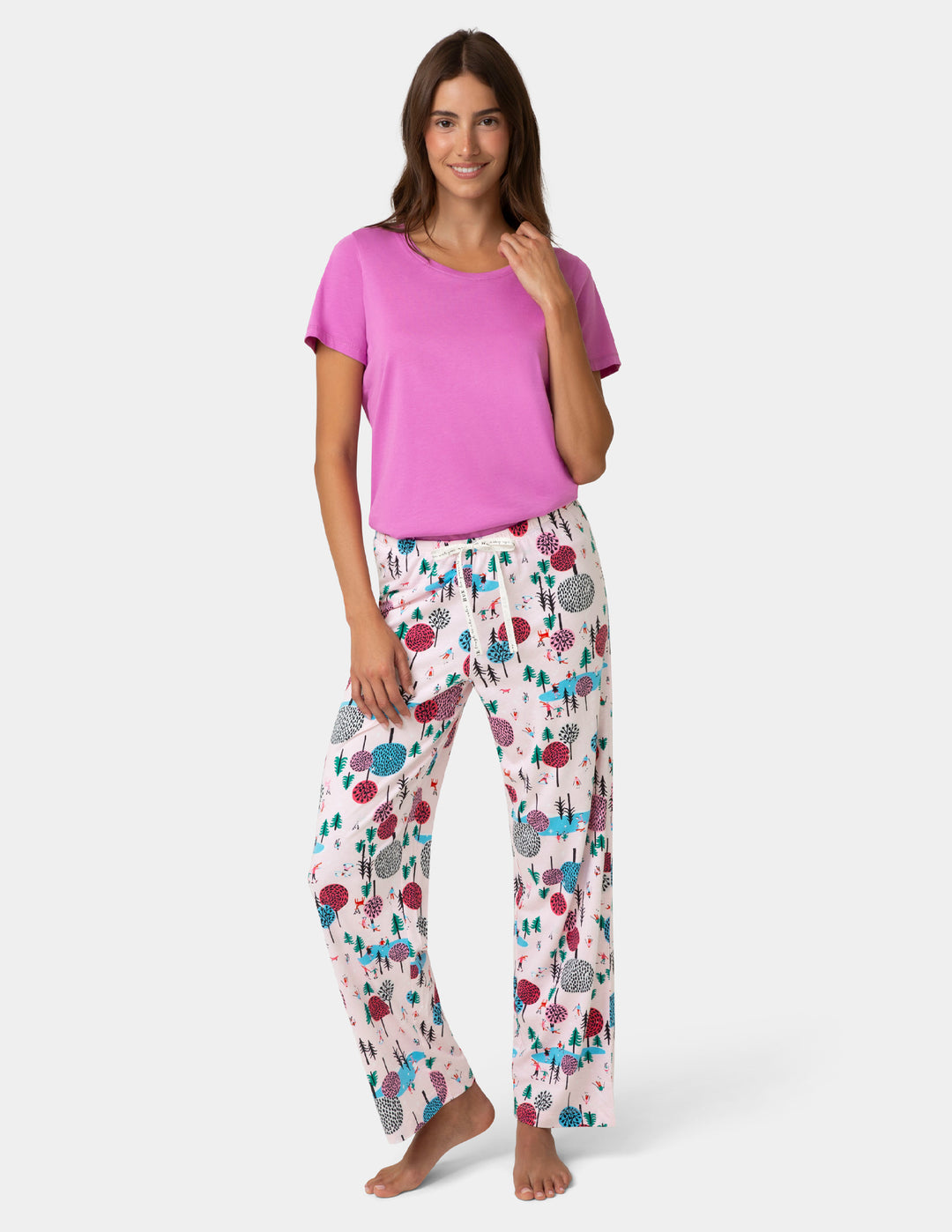 Woman wearing a pink top and patterned pants on a white background