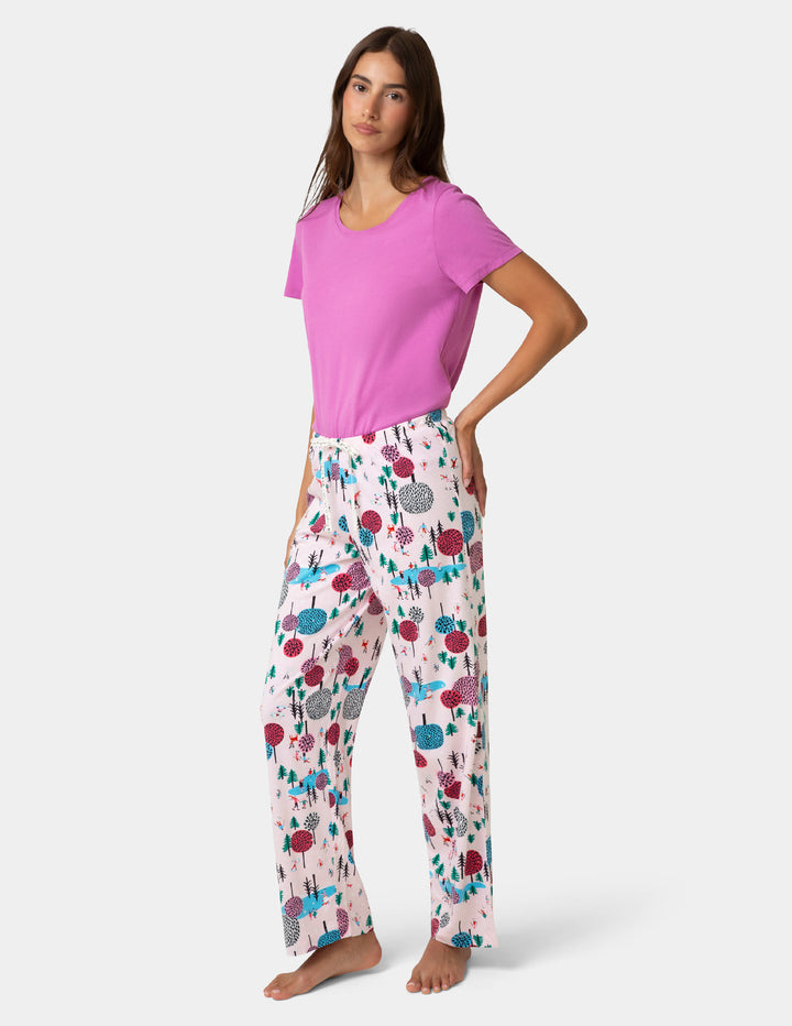 Woman wearing a pink top and floral pajama pants on a white background