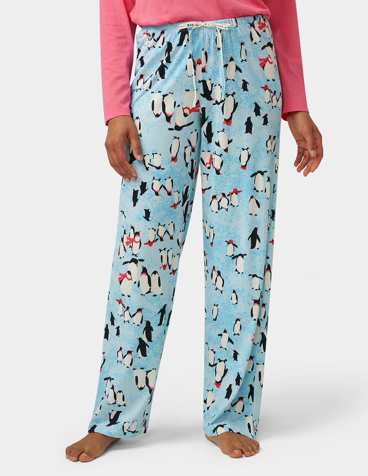 Pajama pants with penguin pattern worn by a person on a white background