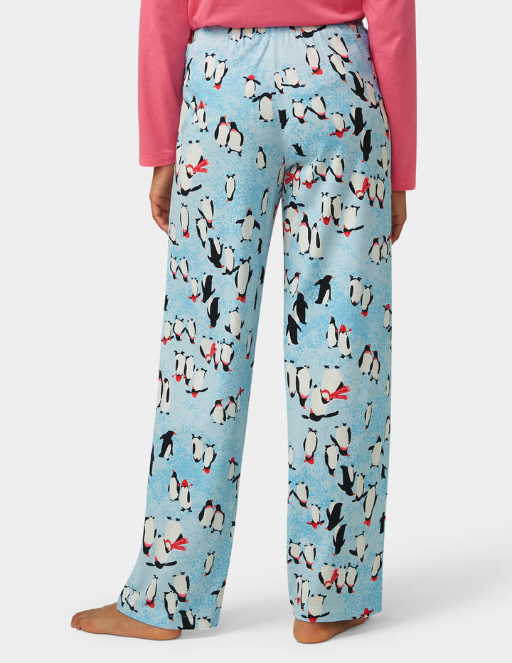 Light blue pajama pants with penguin pattern worn by a person on a white background