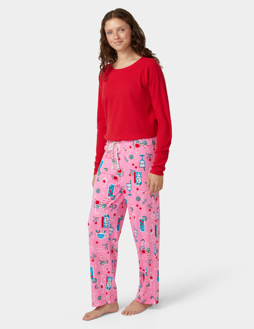 Woman wearing a red top and pink pajama set with cocktails design on a white background