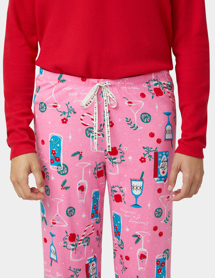 Person wearing pink pajama pants with a festive pattern and a red sweater.