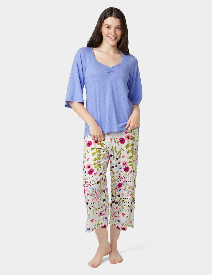 Woman wearing a blue top and floral pants on a white background