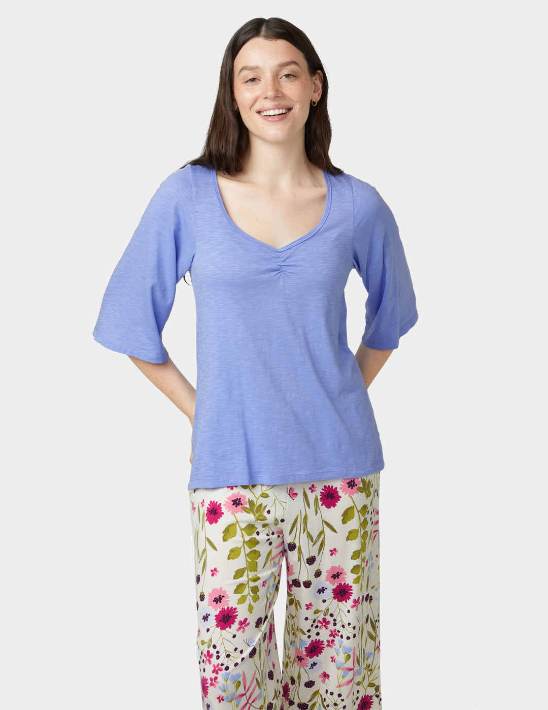 Woman wearing a blue top and floral pants on a white background