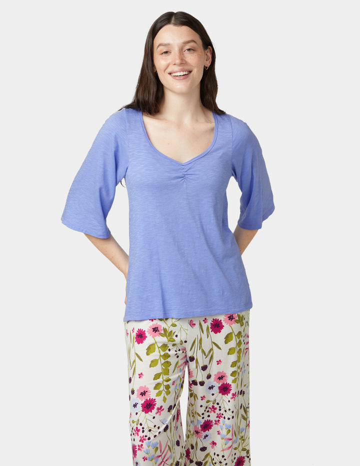Woman wearing a blue top and floral pants on a white background