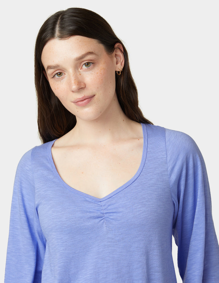 Woman wearing a blue long-sleeve shirt against a light gray background