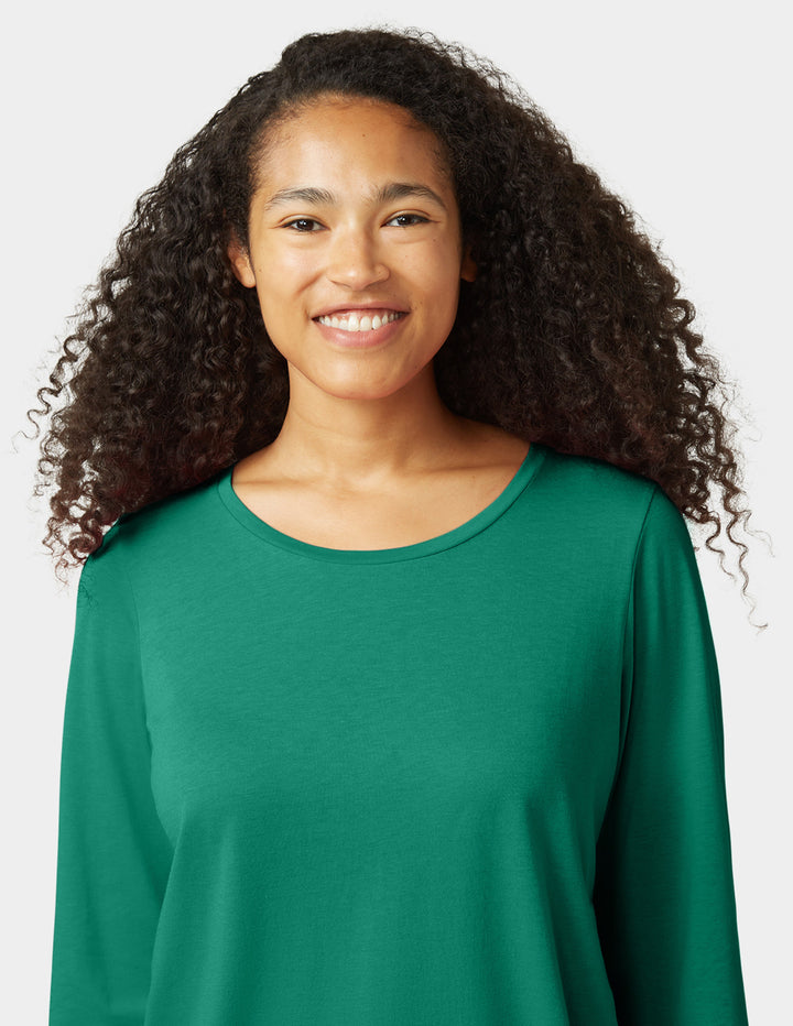 Woman wearing a green long-sleeve shirt against a white background