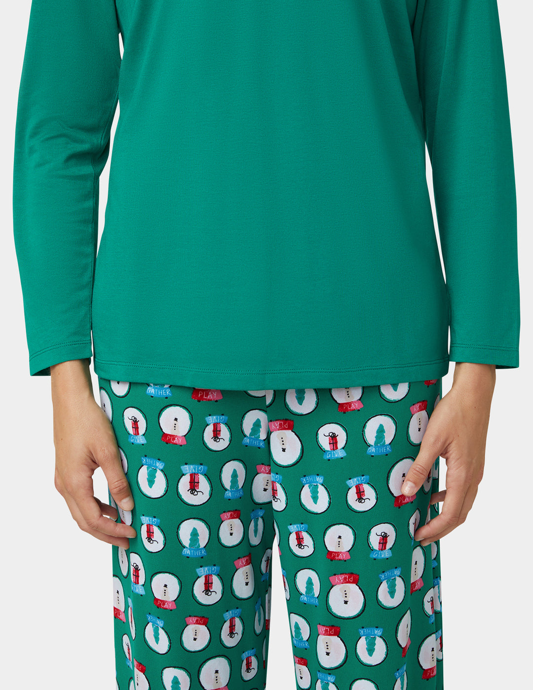 Green long-sleeve top and patterned pants on a white background