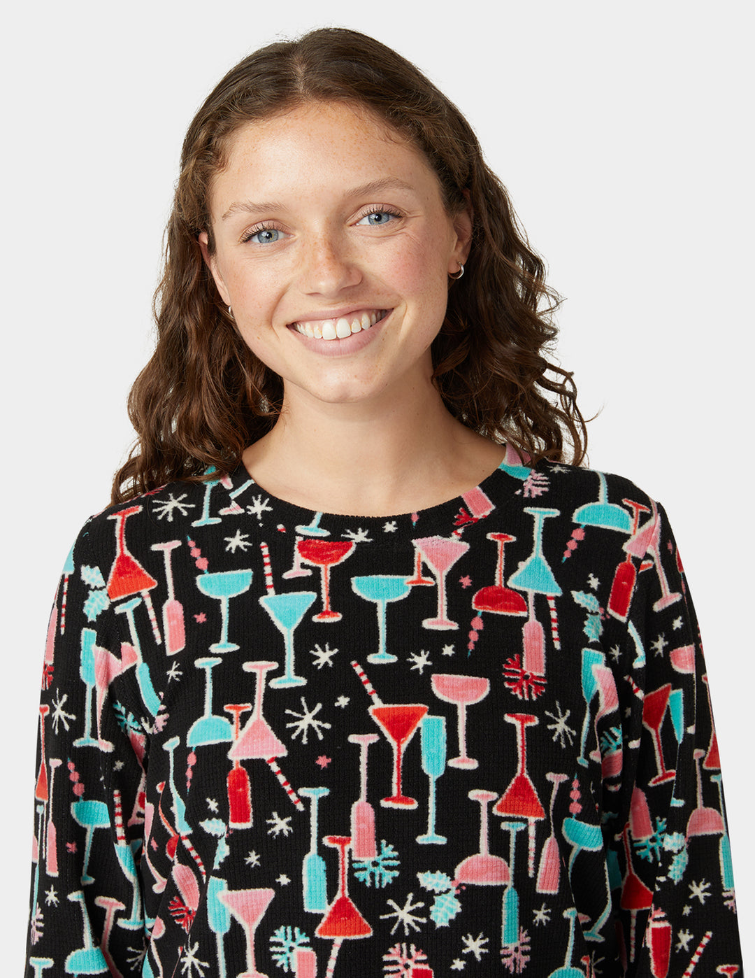 Person wearing a black sweater with colorful cocktail glass pattern on a white background