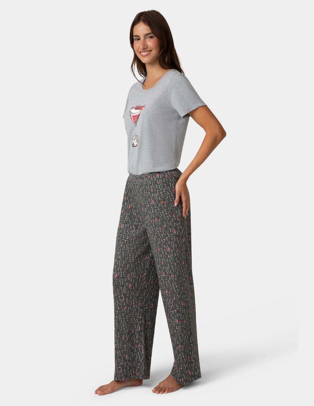 Woman wearing a gray t-shirt with a graphic design and patterned pants on a white background