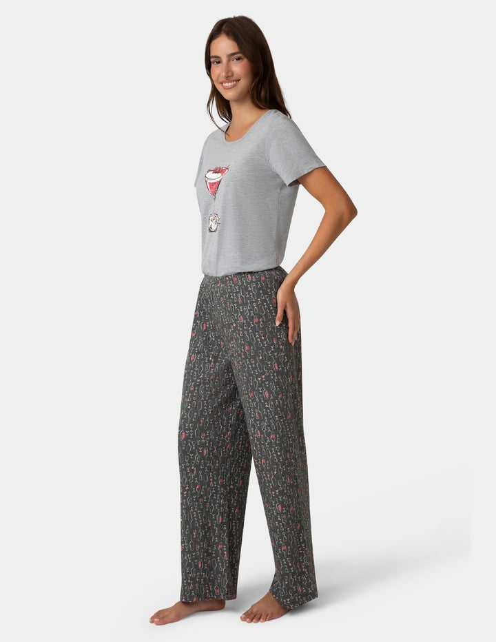 Woman wearing a gray t-shirt with a graphic design and patterned pants on a white background
