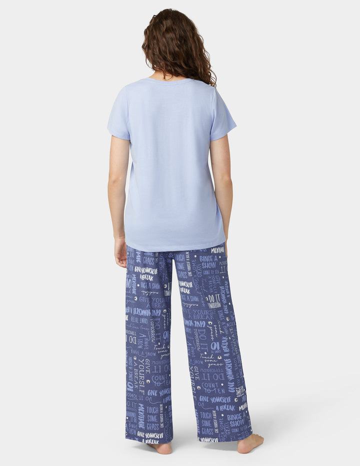 Back view of woman wearing blue pajama set with graphic print bottoms