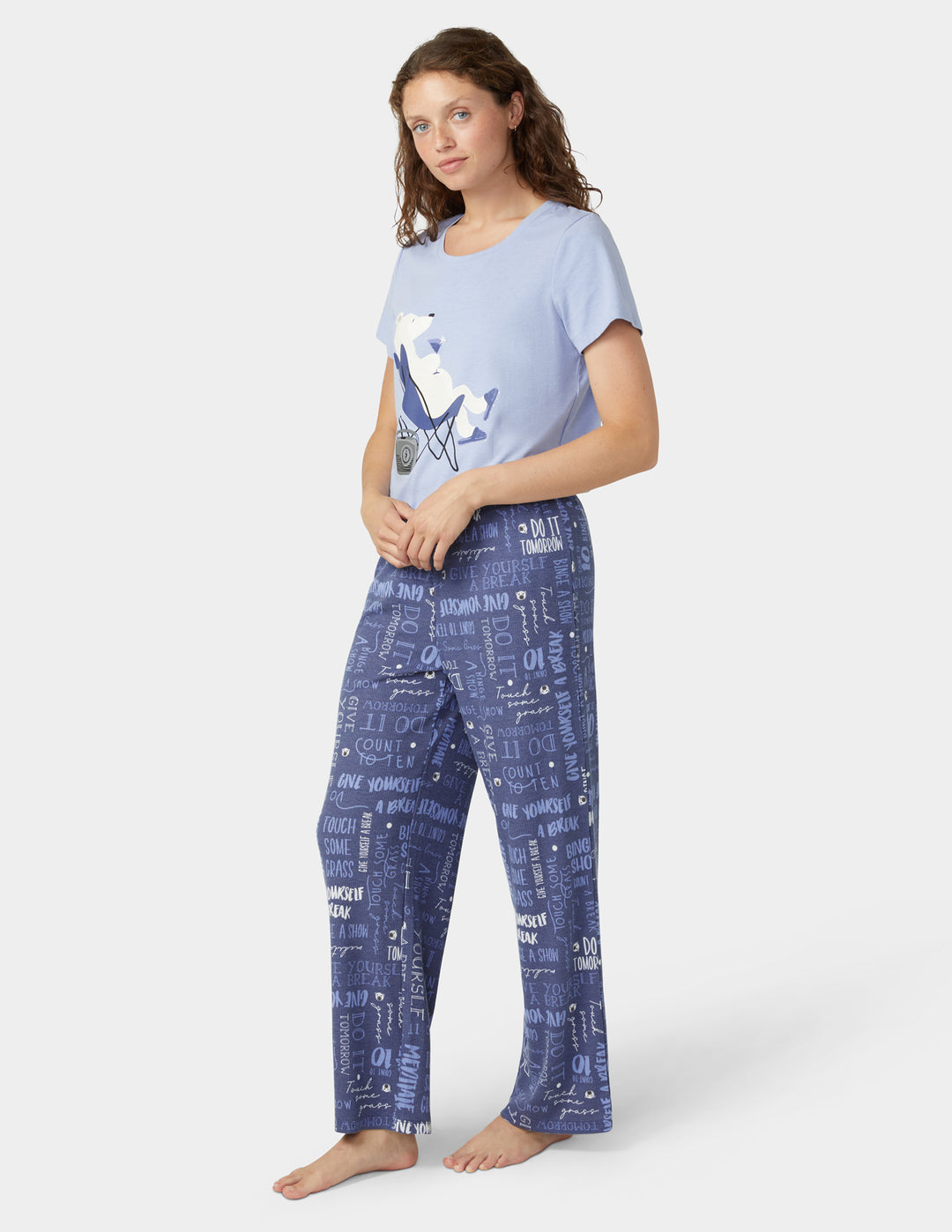 Woman wearing a blue t-shirt and patterned pants on a white background
