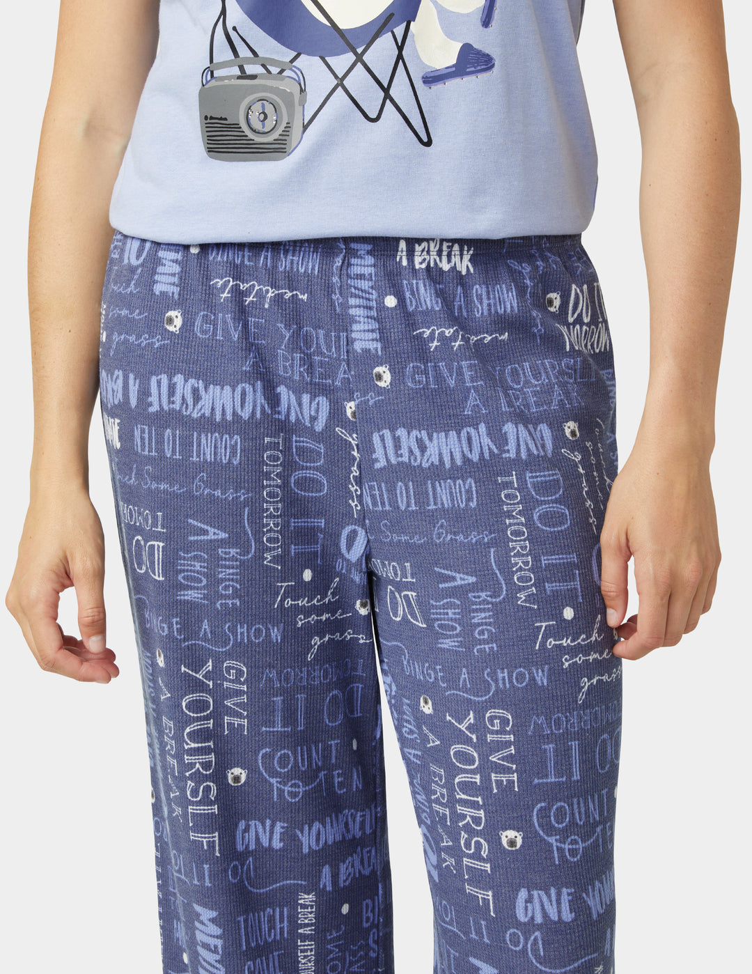 Person wearing a light blue graphic t-shirt and blue pants with text design on a white background