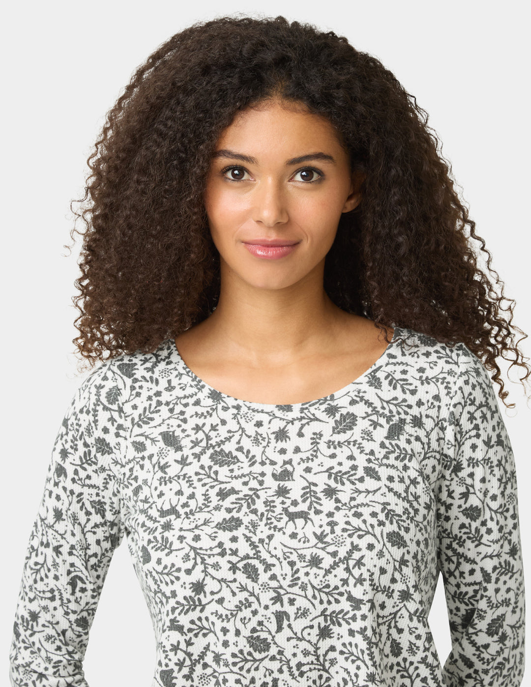 Woman wearing a floral long-sleeve shirt against a plain background