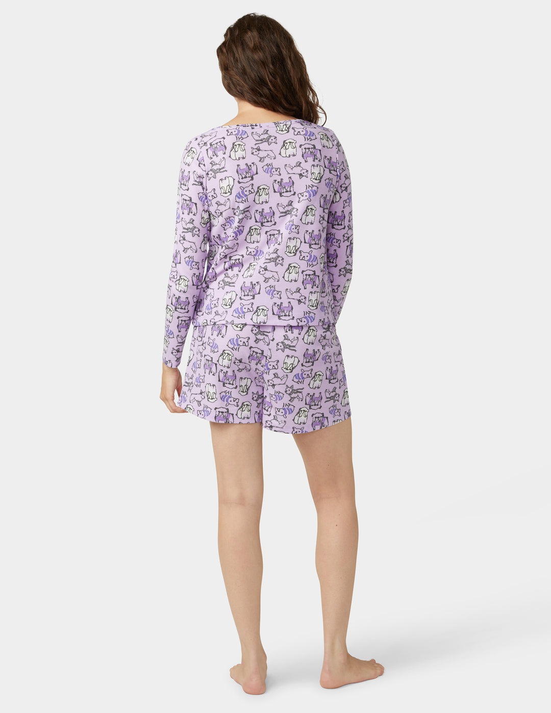 Person wearing a purple pajama set with dogs on a white background