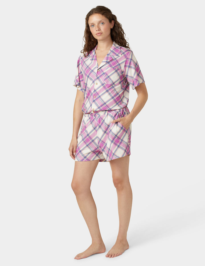Woman wearing a pink and white plaid pajama set on a white background
