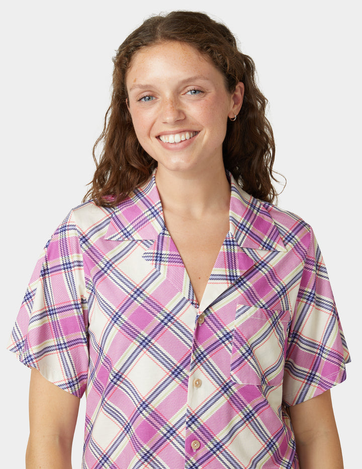 Woman wearing a pink and white plaid shirt on a plain background