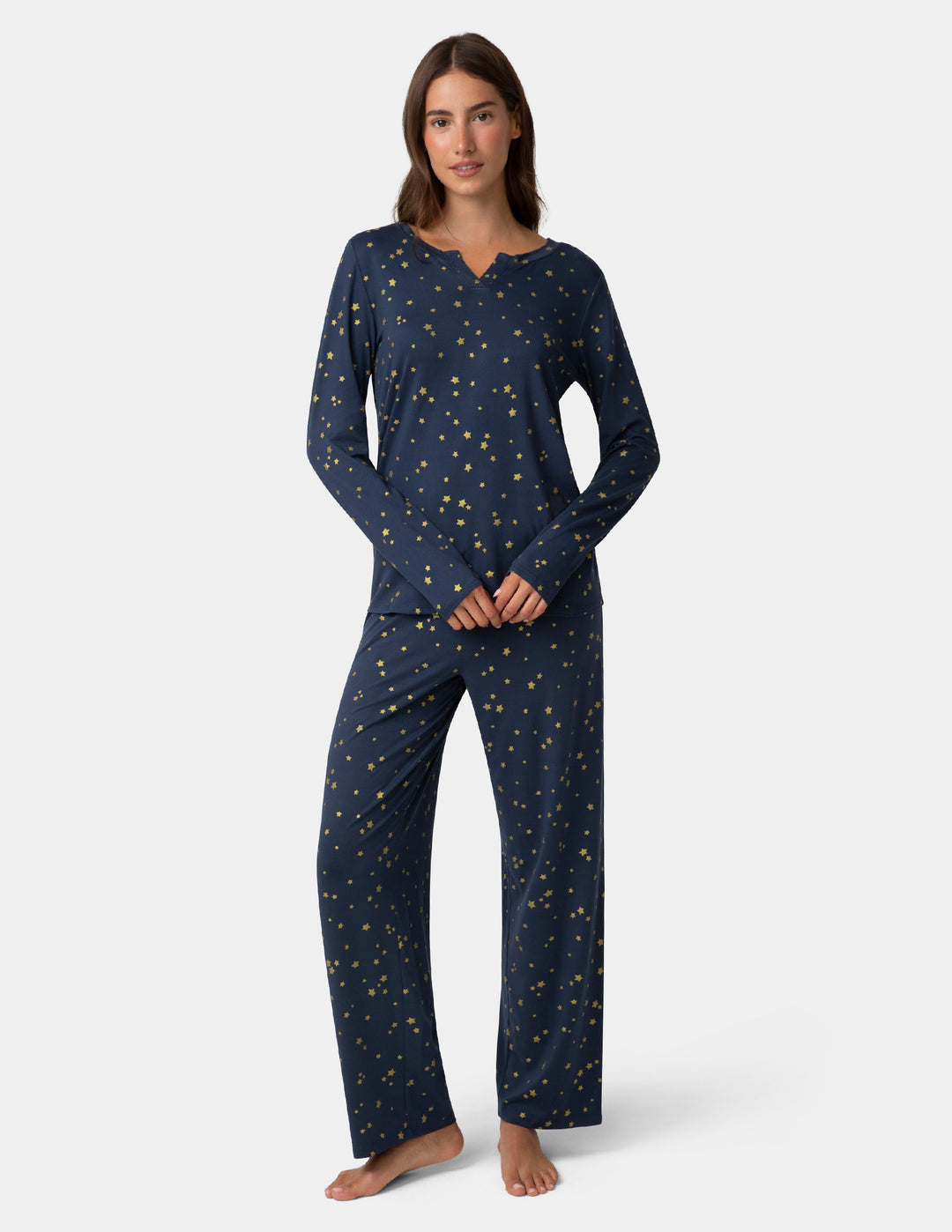 Woman wearing a navy blue pajama set with a star pattern on a white background