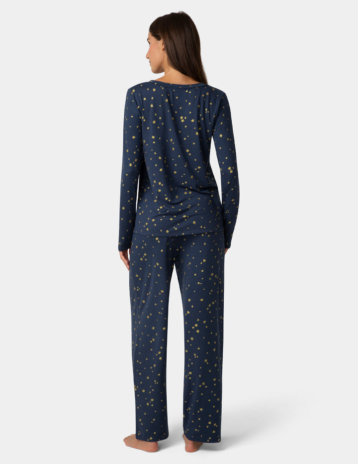 Woman wearing navy blue pajamas with star pattern on a white background