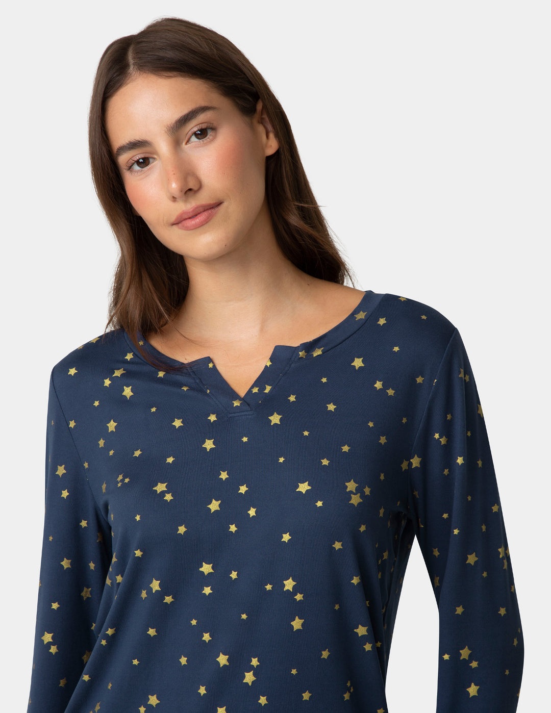 Woman wearing a navy blue long-sleeve shirt with gold star pattern on a plain background