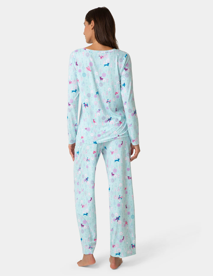 Woman wearing a light blue pajama set with small colorful dog prints on a white background