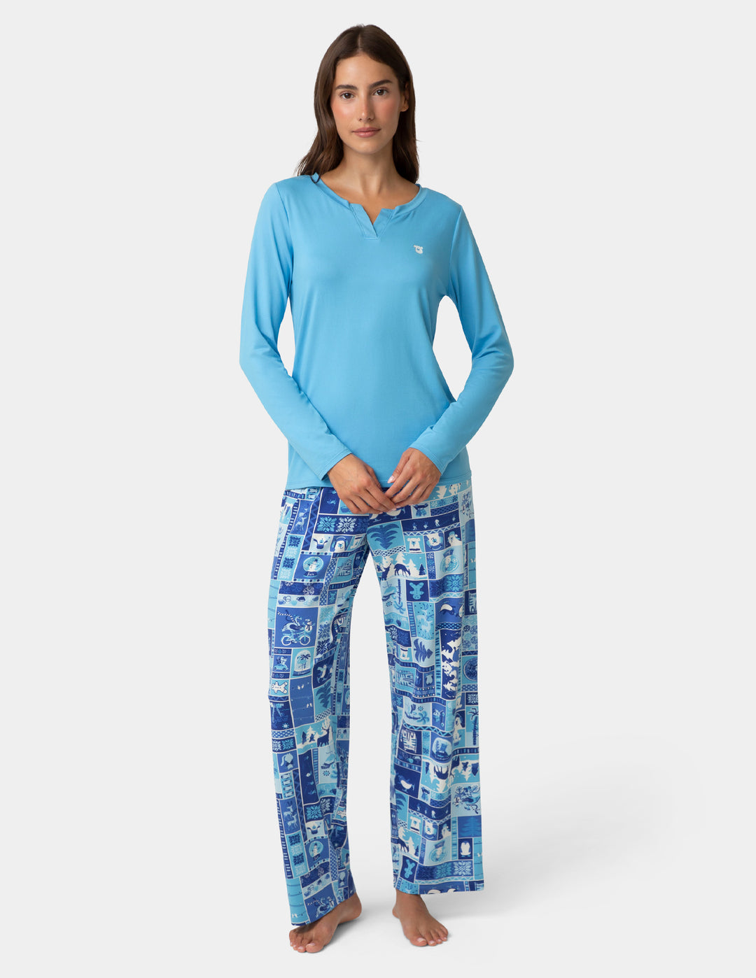 Woman wearing a blue long-sleeve top and patterned blue pants on a white background