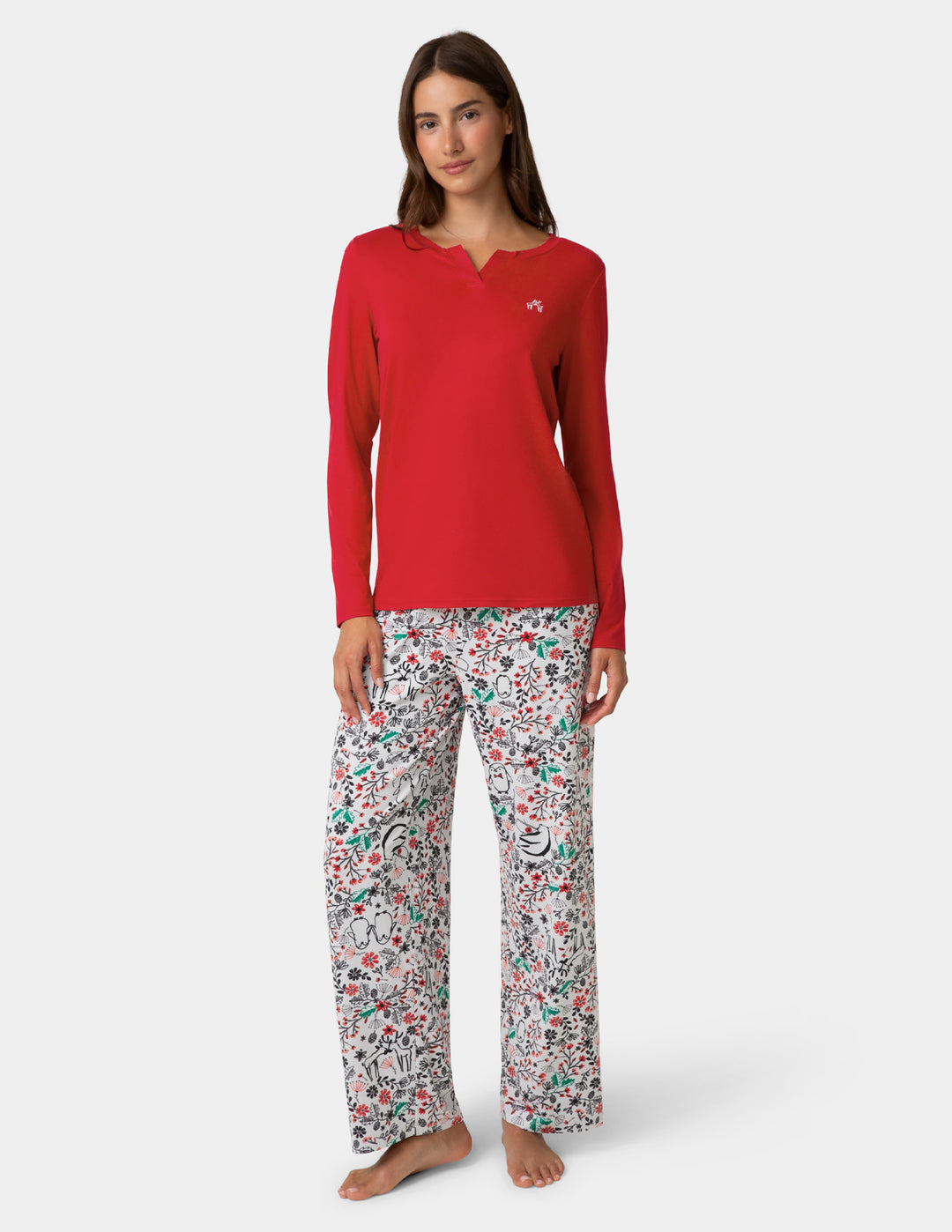 Woman wearing a red long-sleeve top and patterned pajama pants on a white background