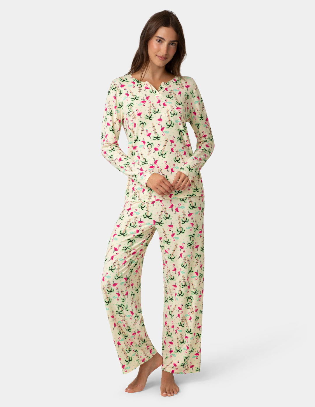 Woman wearing a holiday flamingo and palm tree pajama set on a white background