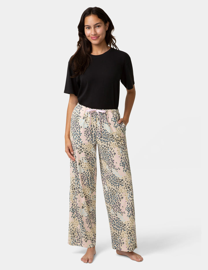 Woman wearing a black top and patterned pants on a white background