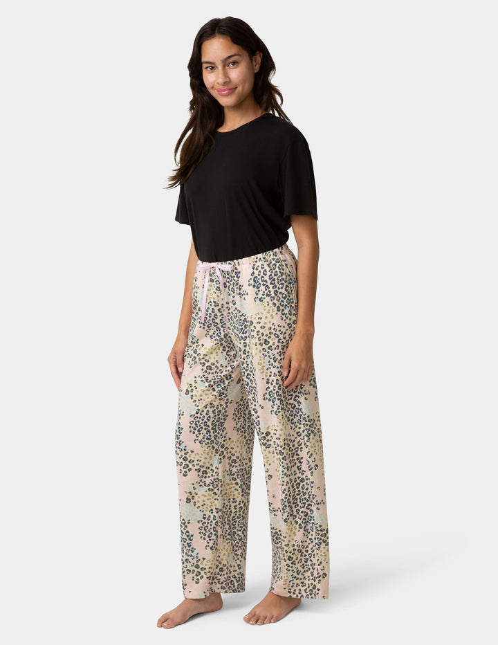 Woman wearing a black top and patterned pants on a white background