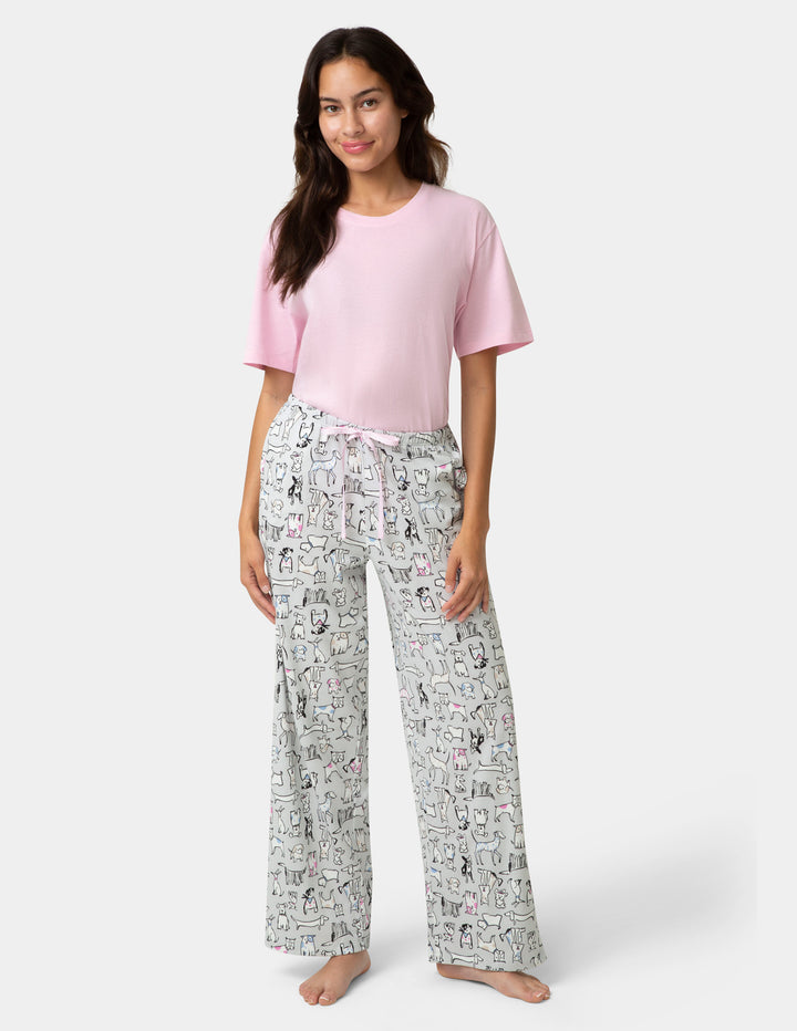 Woman wearing a pink top and patterned pants on a white background