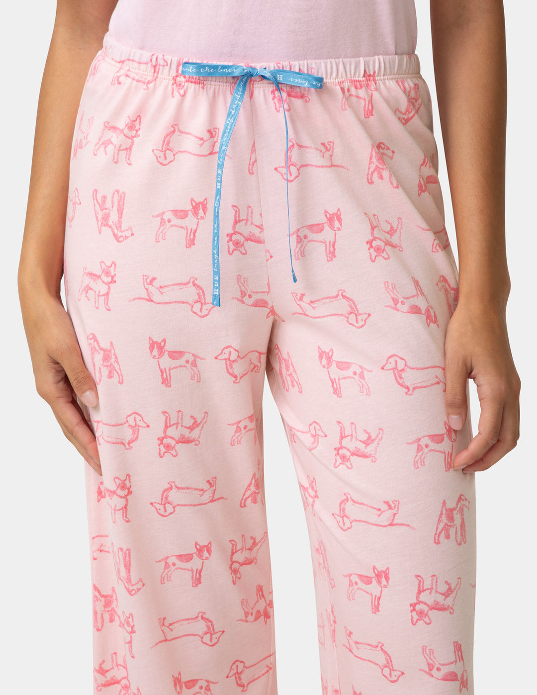Pink pajama pants with dog pattern and blue drawstring on a white background