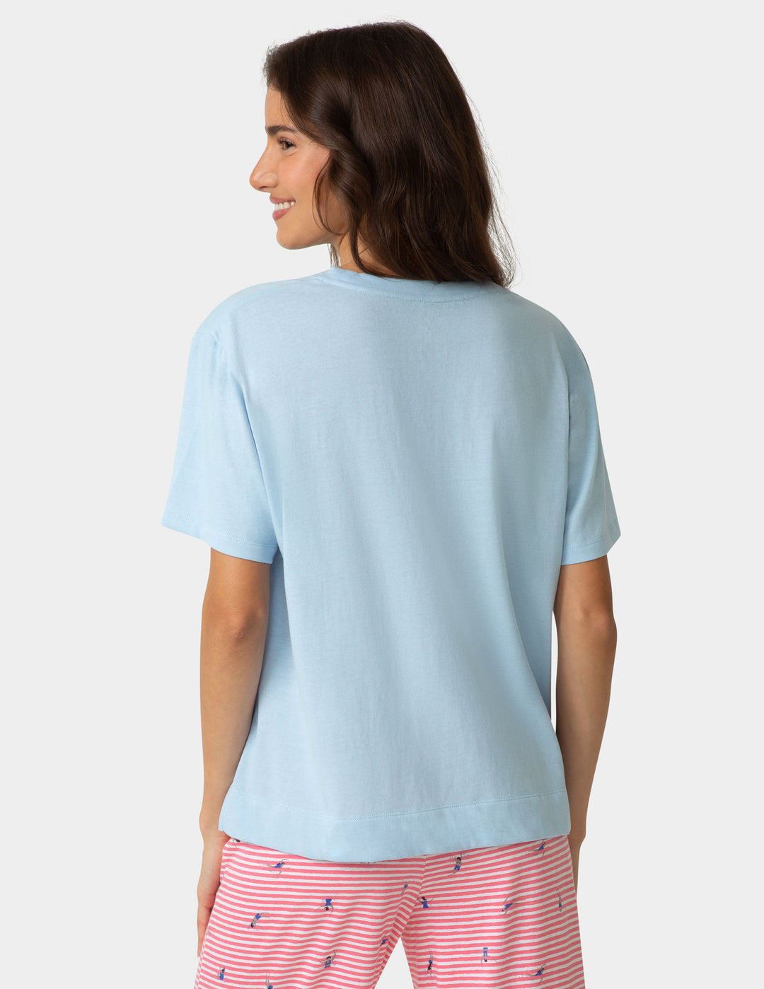 Woman wearing a light blue t-shirt and pink striped pants on a white background