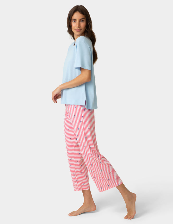Woman wearing a light blue top and pink pajama pants with a white background