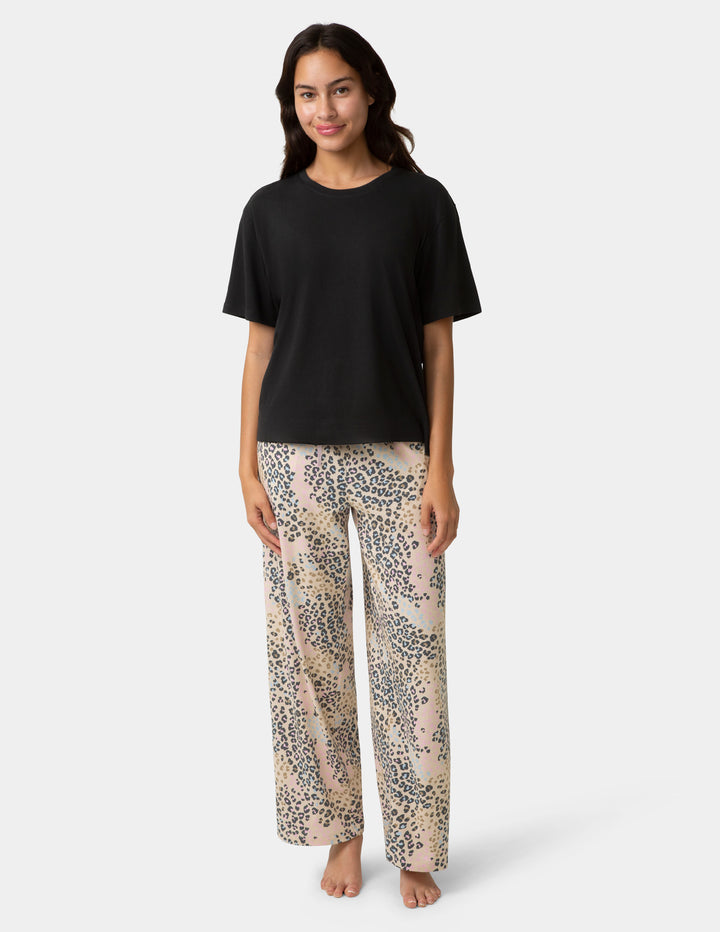 Woman wearing a black top and leopard print pants on a white background