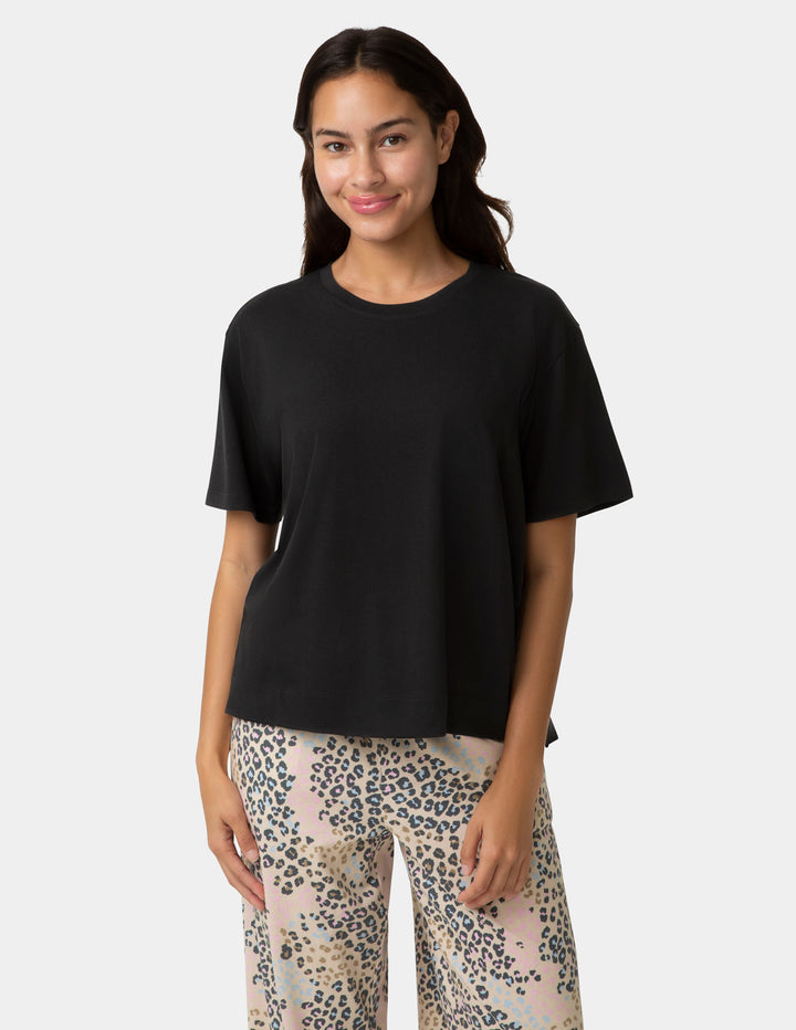 Woman wearing a black t-shirt and leopard print pants on a white background