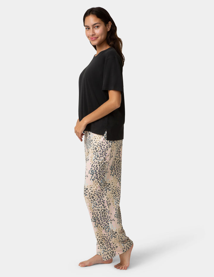Woman wearing a black top and patterned pants on a white background