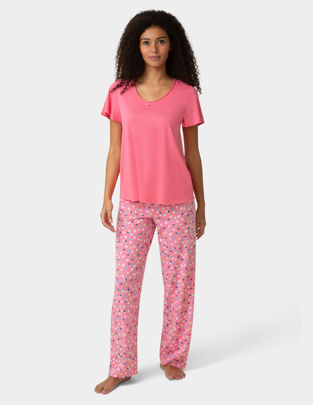 Woman wearing pink pajama shirt and colorful pants on white background