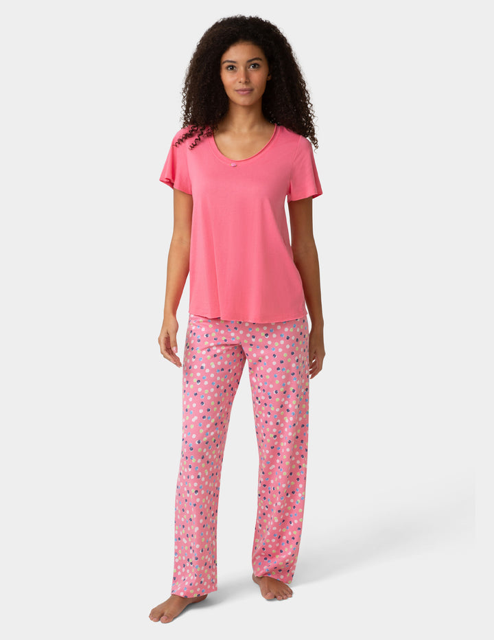 Woman wearing pink pajama shirt and colorful pants on white background