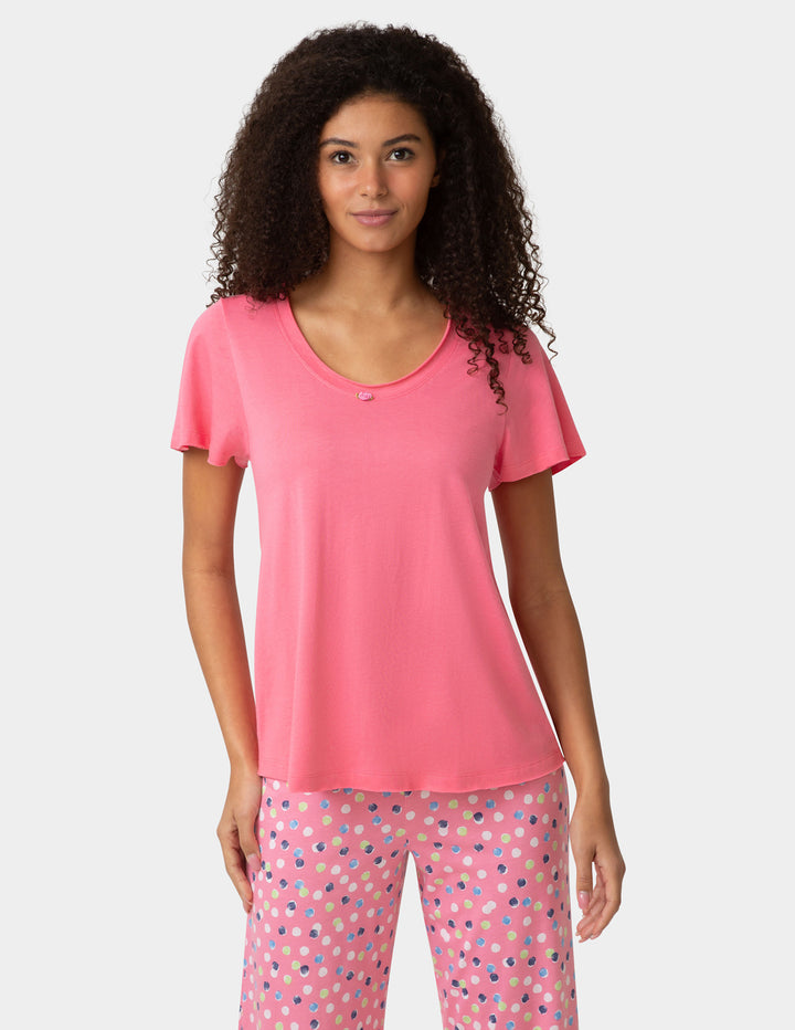 Woman wearing pink pajama shirt and colorful pants on white background
