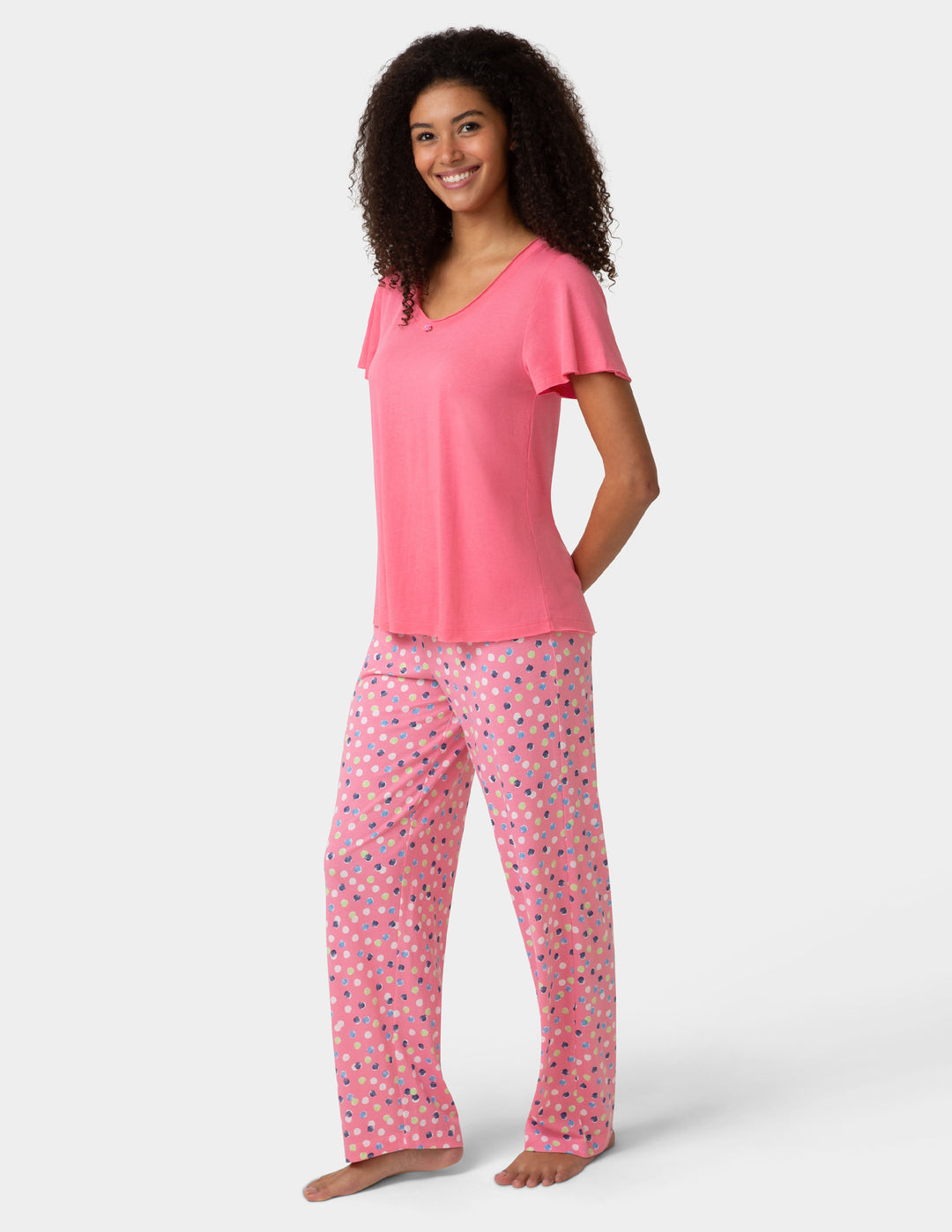 Woman wearing pink pajama shirt and colorful pants on white background