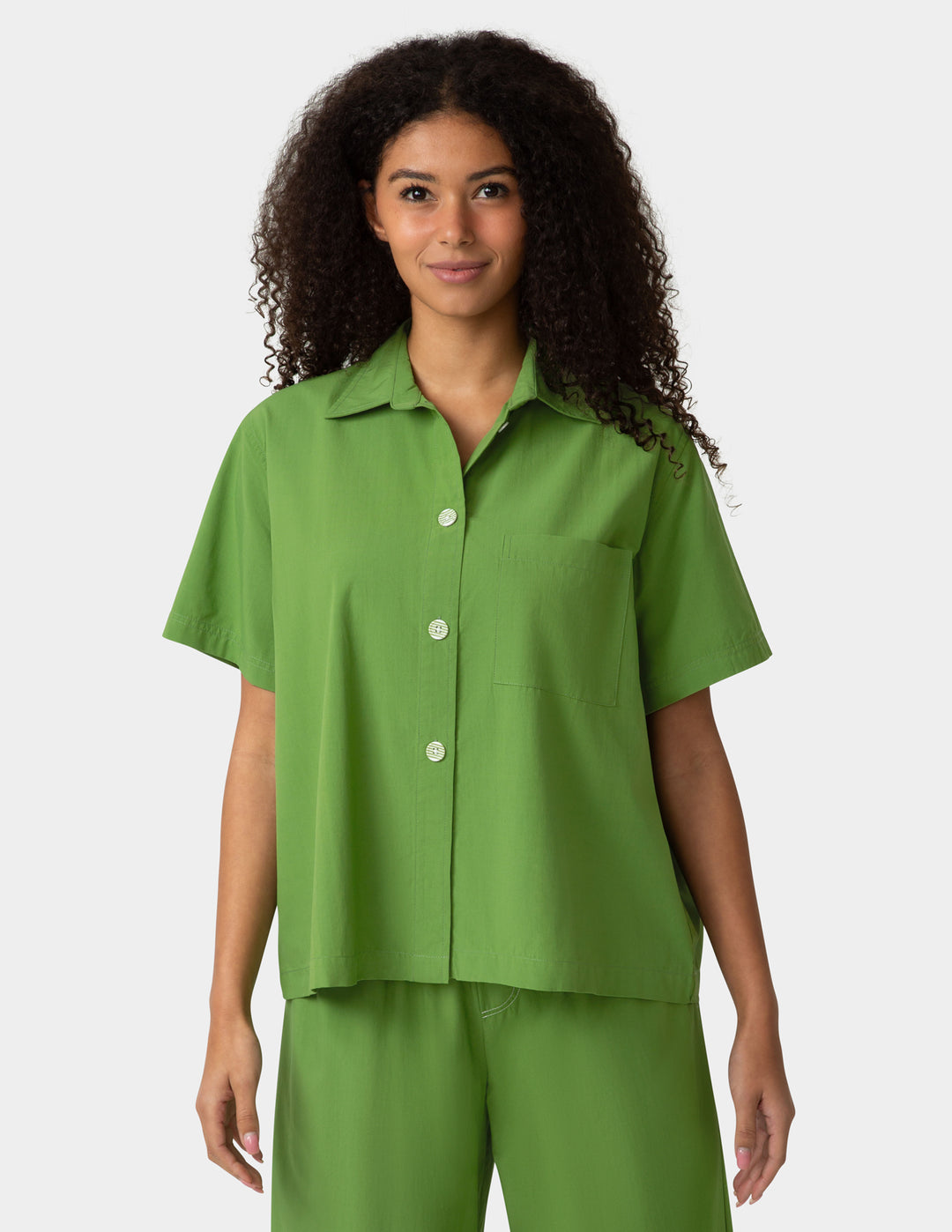 Woman wearing a green outfit with a plain background
