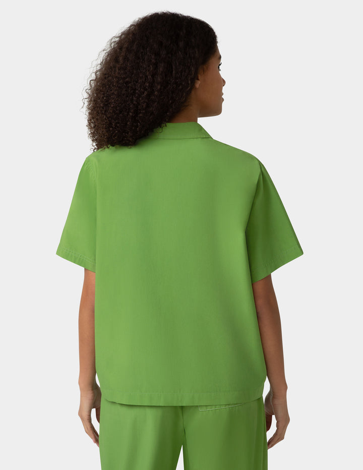 Person wearing a green shirt and pants on a white background