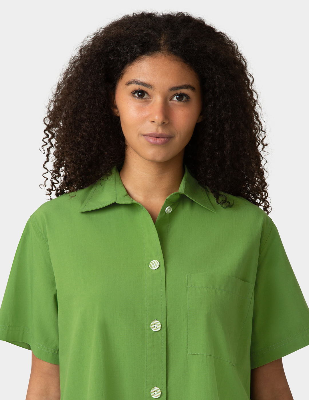 Woman wearing a green shirt against a plain background
