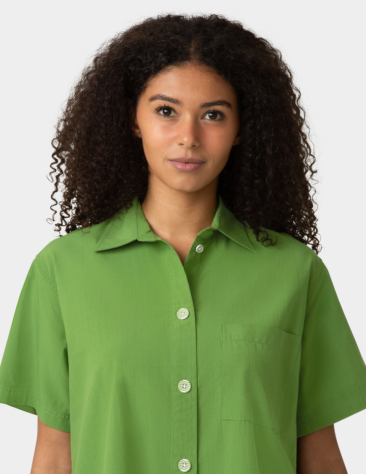 Woman wearing a green shirt against a plain background