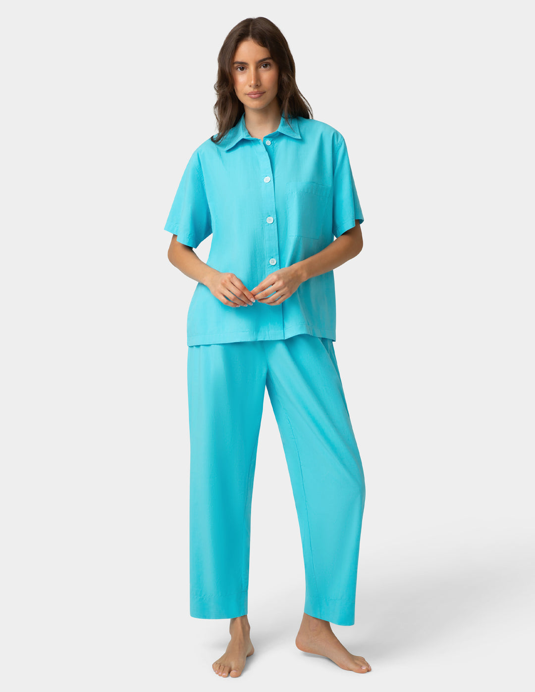 Woman wearing a turquoise pajama set on a white background
