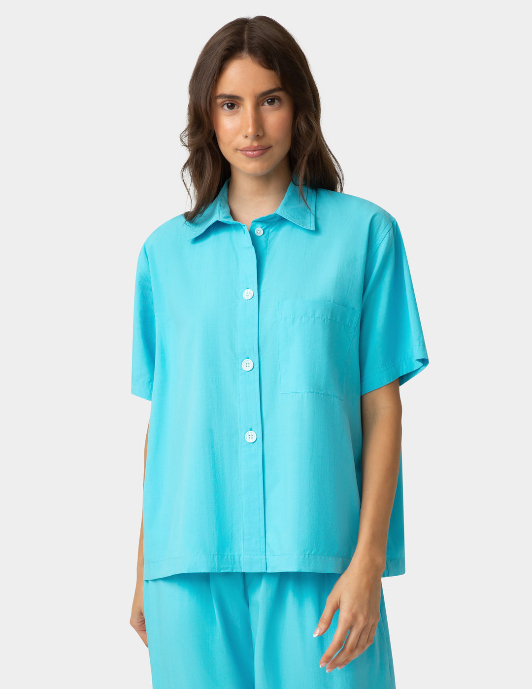 Woman wearing a turquoise shirt and pants on a white background